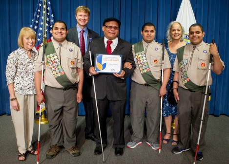 Picture from August 2017 Susan M Daniels Disability Mentoring Hall of Fame Induction Ceremony at the U.S. Department of Education in Washington, DC. On stage with blue curtain behind them stand, from left to right, Rayna Aylward (NDMC Co-Chair), Leo Cantos, Derek Shields (NDMC Co-Chair), Ollie Cantos, Nick Cantos, Jacquelyn Zimmerman (Department of Education), and Steven Cantos. The Cantos gentleman all hold white canes and Leo, Nick and Steven are wearing Boy Scout uniforms. Photo Credit: Joshua Hoover, Department of Education.